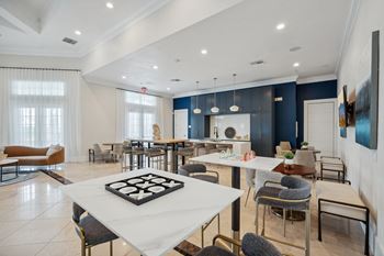 A communal area with tables and chairs and a kitchen and living room